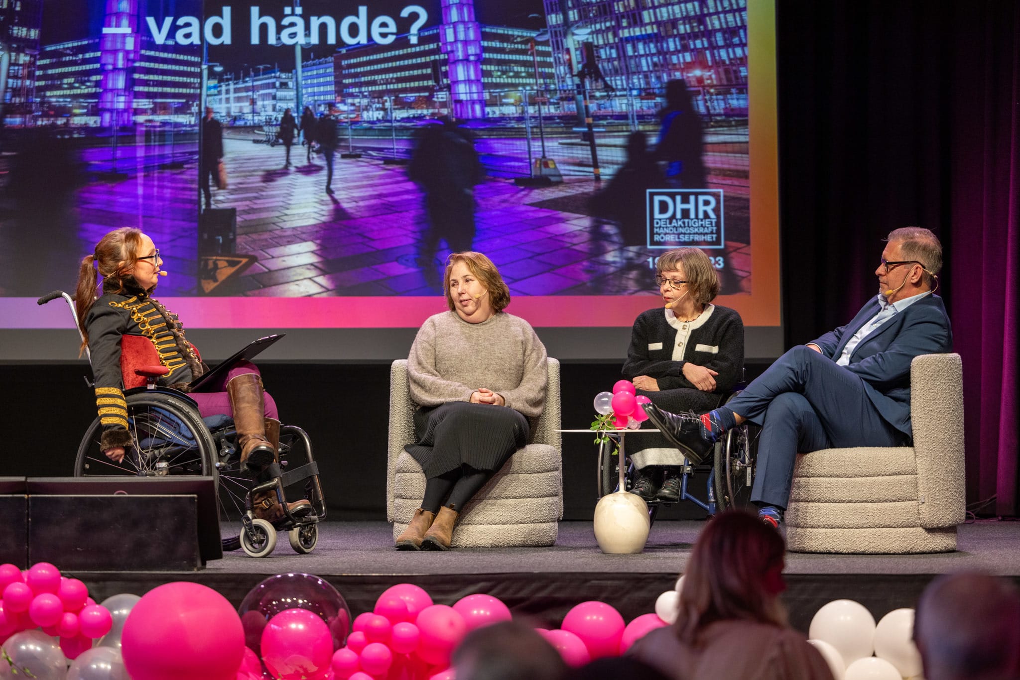 En moderator leder en paneldebatt mellan en man och två kvinnor.